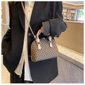 Detail of a brown shell bag with vintage monogram and white contrast straps on black blazer
