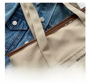 Gros plan détaillé du sac cabas en toile kaki avec bordure en cuir marron et logo