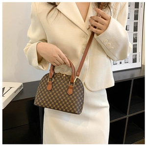 Detail of retro shell bag with brown geometric print and leather handle on a beige suit