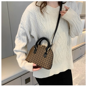 Retro monogram shell bag worn by model with adjustable strap and textured leather finish