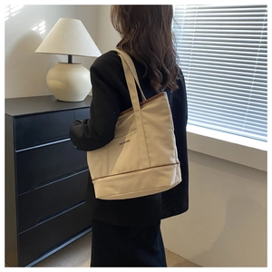 Détail du sac cabas en toile avec poche latérale, bordure brune et logo Meixiaomei