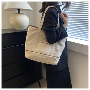 Détail d'un sac cabas en toile blanc cassé avec garniture en cuir porté par un mannequin