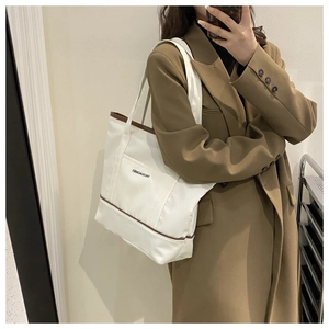 Détail d'un grand sac fourre-tout en toile avec bordure marron et bandoulière au miroir
