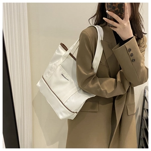 Détail du sac fourre-tout en toile blanche avec bordure en cuir marron et poche