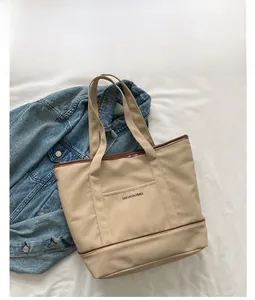 Détail du sac fourre-tout en toile kaki avec garniture en cuir brun et poche frontale