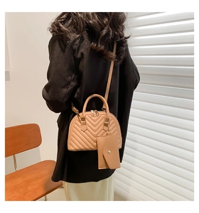 Détail du sac à main beige matelassé à chevrons avec double poignée et bandoulière