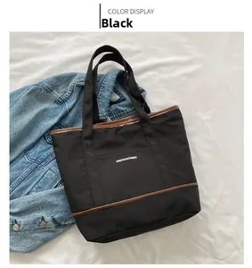 Vue à plat d'un sac cabas en toile noire avec garniture en cuir brun et texte logo