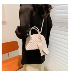 Détail du sac coquille blanc avec surpiqûres en V et petit sac suspendu décoratif
