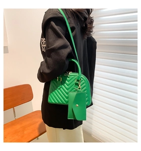 Détail du sac bowling vert matelassé en V avec garniture dorée et mini pochette