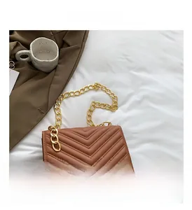Detail of a brown quilted leather crossbody bag with elegant gold chain strap accents
