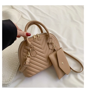 Détail du sac à main matelassé abricot avec boucles dorées et petit porte-monnaie