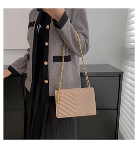 Close-up of beige quilted chain shoulder bag worn with a stylish grey knit jacket