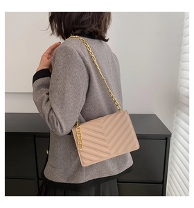 Detailed back view of a beige quilted crossbody bag with a heavy gold chain strap