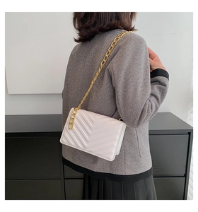 Detail showing white rectangular crossbody bag with V-shaped quilting and gold chain strap