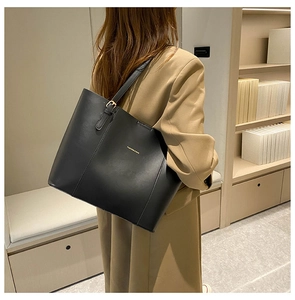 Close-up of a black PU leather tote bag side view with gold lettering and handle