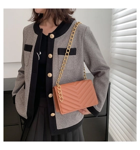 Close-up of brown quilted crossbody bag with gold chain strap on grey tweed coat