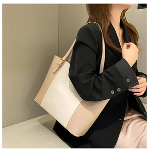 Detail of a large capacity two-tone tote bag in beige and white leather on shoulder
