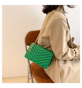 Close-up of bright green V-quilted leather bag with chunky gold chain shoulder strap