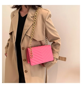 Detail of hot pink quilted crossbody bag featuring V-stitch and gold chain strap
