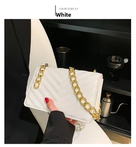 Detail of white quilted crossbody bag with chunky gold chain strap and V-shaped stitching