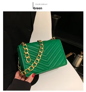 Detail of green faux leather crossbody bag with V-shaped quilting and gold chain strap