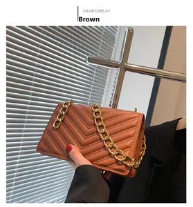 Detail of brown quilted shoulder bag with V-shaped stitching and chunky gold chain strap