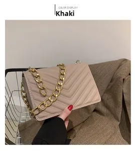 Detail of khaki crossbody bag featuring V-shaped stitching and chunky gold chain strap