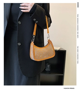 Detail of orange crescent bag featuring silver studs and adjustable shoulder strap