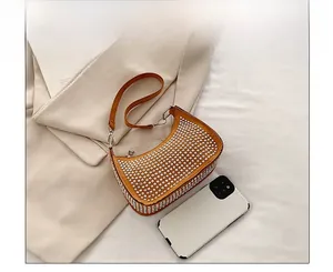 Size comparison of rhinestone crescent bag in ginger yellow beside a white smartphone