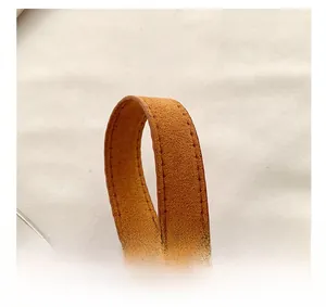 Close-up of brown suede shoulder strap with precise stitching and silver metal buckle