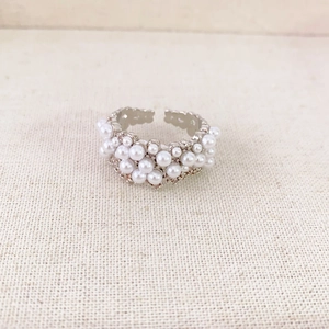 Luxurious silver ring with multi-pearl clusters on rustic linen background