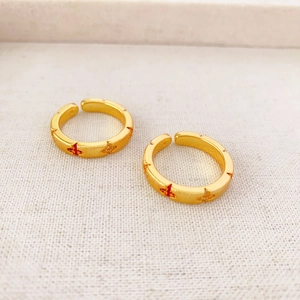 Detail of adjustable gold-plated rings with matte texture and colorful star patterns