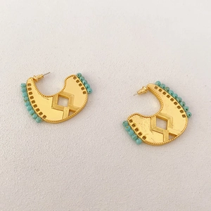 Detail of tribal style crescent earrings with gold plating and turquoise beads