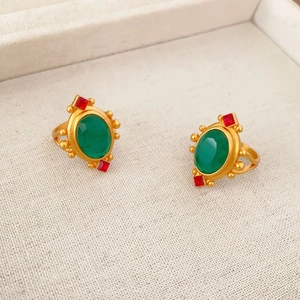 Gros plan d'une bague dorée vintage avec cristal vert et pierres d'accent rouges