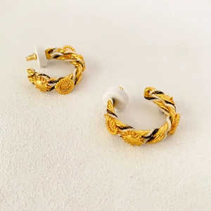 Détail de boucles d'oreilles créoles dorées tressées avec reliefs de tournesol et argent 925