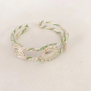 Bracelet manchette tressé argenté avec fil de soie vert et pendentif soleil
