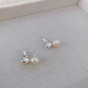 Boucles d'oreilles minimalistes en argent 925 avec perles blanches sur tissu beige