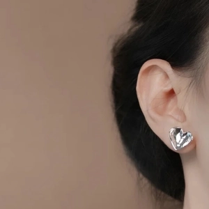 Minimalist heart stud earring in silver finish with fluid metal texture on female model