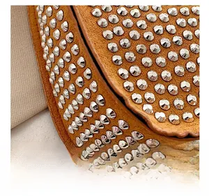 Close-up of brown suede bag featuring silver metal rivets and precision stitching details