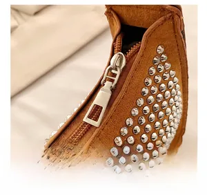 Detail of high-quality golden zipper and silver rivets on brown suede crescent bag