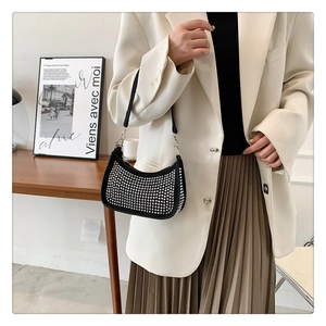 Close-up of black hobo bag with silver rhinestone studs on model wearing white blazer