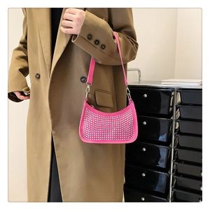 Close-up of bright pink rhinestone moon bag worn with a camel coat for a chic look