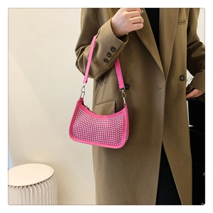 Detailed view of the sparkling hot pink rhinestone hobo bag worn by a model