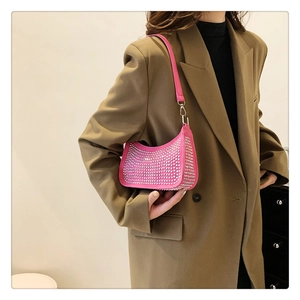 Detailed view of shimmering silver rhinestones on a bright pink crescent-shaped baguette bag