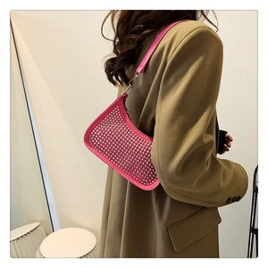Detail of rose pink rhinestone crescent shoulder bag worn with a brown blazer