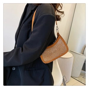 Detail of orange-brown hobo bag with rhinestone rows worn by model in black suit