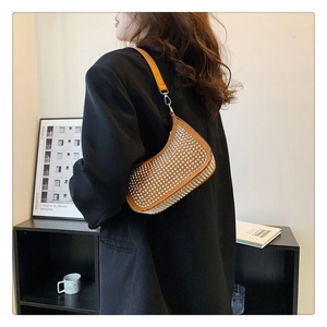 Close-up of orange rhinestone saddle bag showing metallic stud texture and shoulder strap