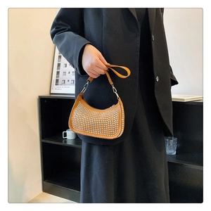 Detail of tan crescent shoulder bag with silver metallic studs and detachable strap