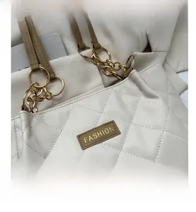 Detail of white quilted leather bag featuring gold chain and FASHION leather tag