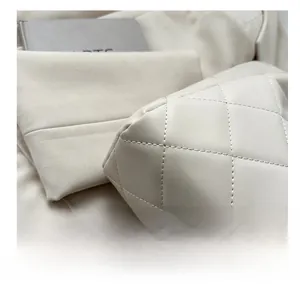 Detailed view of quilted leather texture and stitching on the cream white tote bag